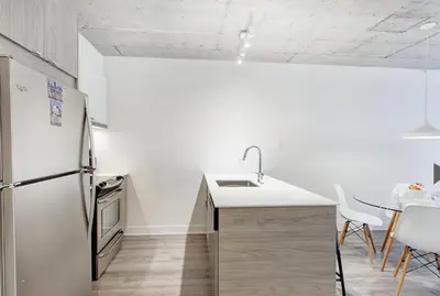 a white kitchen with a refrigerator and a table at Montreal rent in Montréal