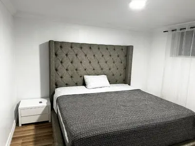 a bedroom with a bed with a padded headboard at Appartement en étage in Mascouche