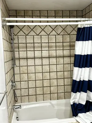 a bathroom with a tub and a tiled wall at Appartement en étage in Mascouche