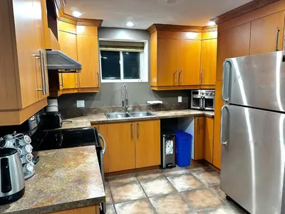 a kitchen with wooden cabinets and a stainless steel refrigerator at Appartement en étage in Mascouche