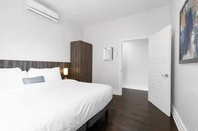 a bedroom with a white bed and a white closet at The Parc Mile End ApartHotel in Montréal