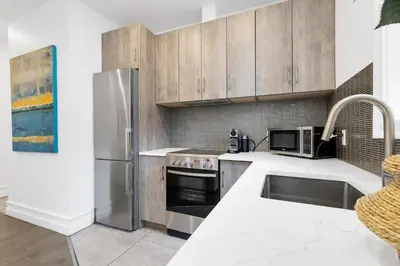 a kitchen with a stainless steel refrigerator and a sink at The Parc Mile End ApartHotel in Montréal