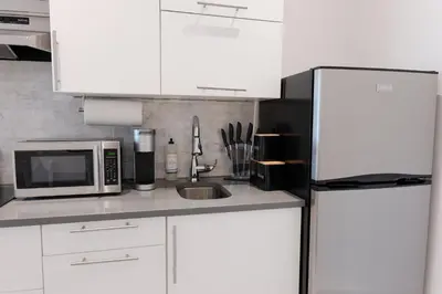 a white kitchen with a microwave and a refrigerator at #4 - Quaint Studio - Self Check in - Plateau - St-Denis - AC - TV in Montréal