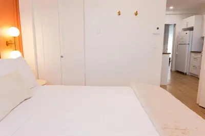 a white bedroom with a white bed and a kitchen at #5 - Spacious 3Bds - Self Check in - Plateau - St-Denis - AC - TV in Montréal