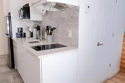 a white kitchen with a sink and a refrigerator at #7 - Charming Studio - Self Check in - Plateau - St-Denis - AC - TV in Montréal