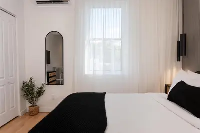 a bedroom with a white bed and a mirror at #8 - Refined Studio - Self Check in - Plateau - St-Denis - AC - TV in Montréal