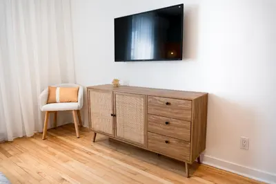 a wooden dresser with a chair and a television on a wall at #10 - Serene Studio - Self Check in - Plateau - St-Denis - AC - TV in Montréal
