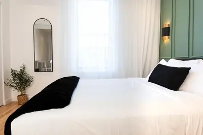 a white bed with black pillows in a bedroom at #11 - Upscale Studio - Self Check in - Plateau - St-Denis - AC - TV in Montréal