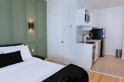 a bedroom with a white bed and a kitchen at #11 - Upscale Studio - Self Check in - Plateau - St-Denis - AC - TV in Montréal