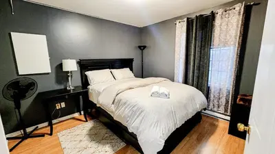 a bedroom with a bed with white sheets and a window at Condo de charme familial in Brossard