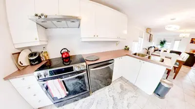 a kitchen with white cabinets and a stove and a sink at Condo de charme familial in Brossard