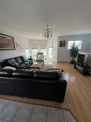 a living room with a black leather couch and a television at Condo de charme familial in Brossard