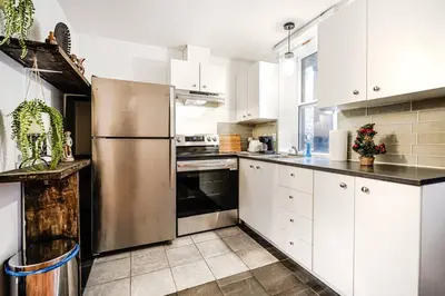 a kitchen with white cabinets and a stainless steel refrigerator at Charmant appartement de 2 chambres à Griffintown in Montréal