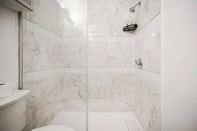 a white bathroom with a shower with a toilet at Charmant appartement de 2 chambres à Griffintown in Montréal