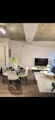 a living room with a table and chairs and a tv at Condo 2 chambres avec parking privé - Griffintown in Montréal