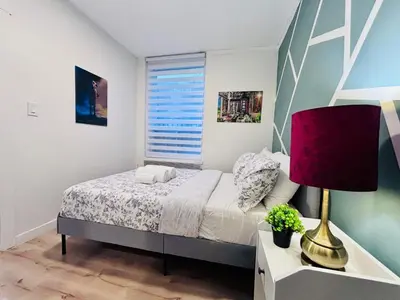 a bedroom with a bed and a lamp and a window at Small but Equipped Unit in Montréal