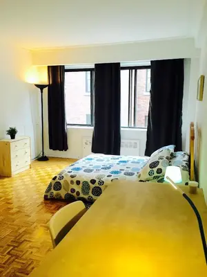 a bedroom with a bed and a table and windows at Stylish Montreal Apartment Comfortable Stay in the Golden Square Mile in Montréal