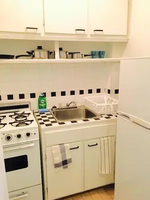 a white kitchen with a sink and a stove at Stylish Montreal Apartment Comfortable Stay in the Golden Square Mile in Montréal