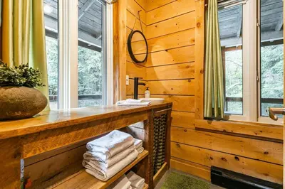 a wooden bathroom with a sink and a window at Le 10 - Spa Sauna Shower Bromont Lac-Brome in Bromont