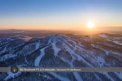a sunset on the top of a snow covered mountain at Le 10 - Spa Sauna Shower Bromont Lac-Brome in Bromont