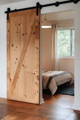 a sliding barn door in a bedroom with a bed at Chalet Chti - bord de l'eau mont Orford in Eastman