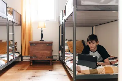 a boy laying on a laptop in a bunk bed at Chalet Chti - bord de l'eau mont Orford in Eastman