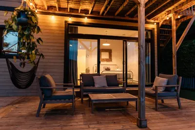 a patio with chairs and a table and a bed at Chalet Chti - bord de l'eau mont Orford in Eastman