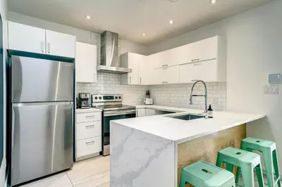 a kitchen with white cabinets and a stainless steel refrigerator at Spacious Group Haven Near Trendy St Laurent in Montréal