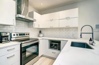 a kitchen with white cabinets and a sink at Spacious Group Haven Near Trendy St Laurent in Montréal