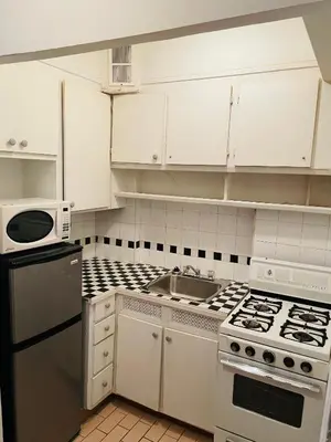 a white kitchen with a stove and a sink at Stylish Montreal Apartment Comfortable Stay in the Golden Square Mile in Montréal