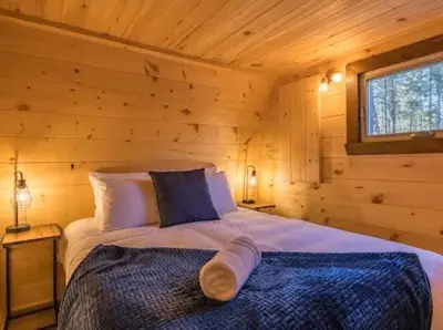a bedroom with a bed in a log cabin at Le POD du Mont ADSTOCK spa ski motoneige VTT plein air arcade in Adstock