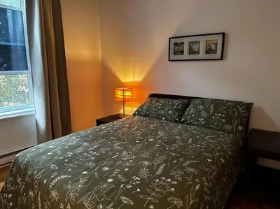 a bedroom with a bed and a lamp and a window at Fully furnished 2 bedroom unit, downtown, near subway, 32 days minimum in Montréal