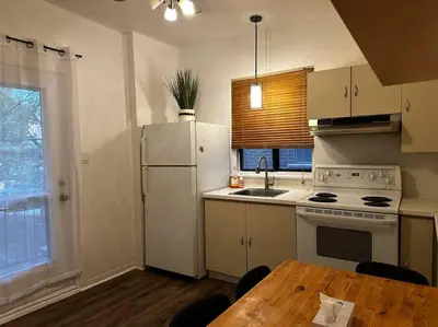 a kitchen with a table and a white refrigerator at Fully furnished 2 bedroom unit, downtown, near subway, 32 days minimum in Montréal