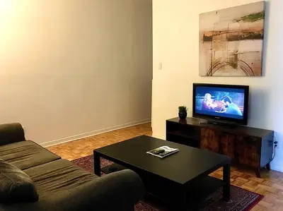 a living room with a couch and a table with a tv at Fully furnished 2 bedroom unit, downtown, near subway, 32 days minimum in Montréal