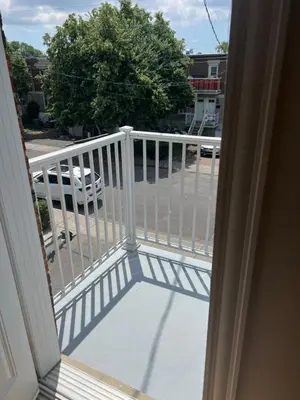 a balcony with a white railing and a car at Chambres à louer in Montréal