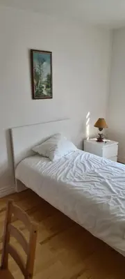 a bedroom with a bed with a chair and a picture on the wall at Chambres à louer in Montréal