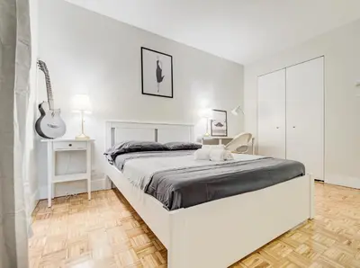 a white bedroom with a white bed and a guitar at Cozy 2-Bedroom à Plateau-Mont-Royal in Montréal
