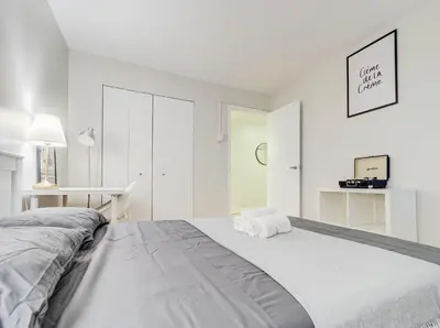 a white bedroom with a bed with towels on it at Cozy 2-Bedroom à Plateau-Mont-Royal in Montréal