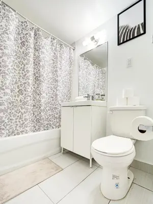 a white bathroom with a toilet and a shower curtain at Cozy 2-Bedroom à Plateau-Mont-Royal in Montréal
