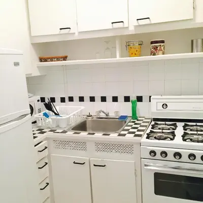 a white kitchen with a sink and a stove at Stylish Montreal Apartment Comfortable Stay in the Golden Square Mile in Montréal