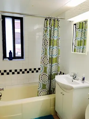 a bathroom with a tub and a sink and a shower curtain at Stylish Montreal Apartment Comfortable Stay in the Golden Square Mile in Montréal