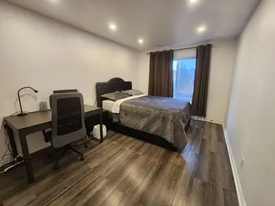 a bedroom with a bed and a desk and a computer at Perle Urbaine Chic et confort in Longueuil