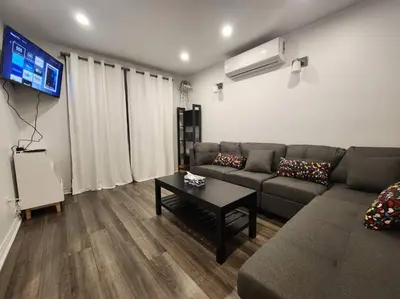 a living room with a couch and a tv at Perle Urbaine Chic et confort in Longueuil