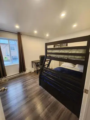 a bedroom with a bunk bed and a wooden floor at Perle Urbaine Chic et confort in Longueuil