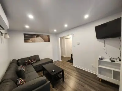 a living room with a couch and a flat screen tv at Perle Urbaine Chic et confort in Longueuil