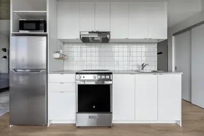a white kitchen with a stove and a refrigerator at Appartements Dorchester in Montréal