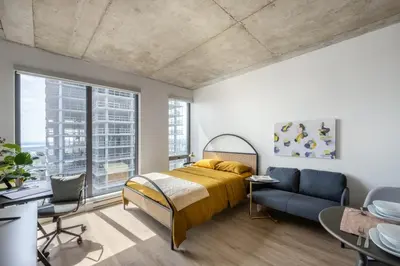 a bedroom with a bed and a desk and a couch at Appartements Dorchester in Montréal