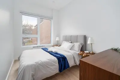 a white bedroom with a large bed and a window at The S&D Apartments in Montréal