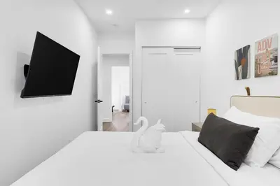 a white bedroom with a bed with a tv on the wall at Boutique 4BR Luxury Residence 2 Floors Mile-End St-Laurent in Montréal