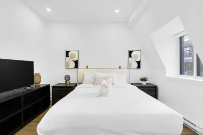 a white bedroom with a large bed and a flat screen tv at Boutique 4BR Luxury Residence 2 Floors Mile-End St-Laurent in Montréal